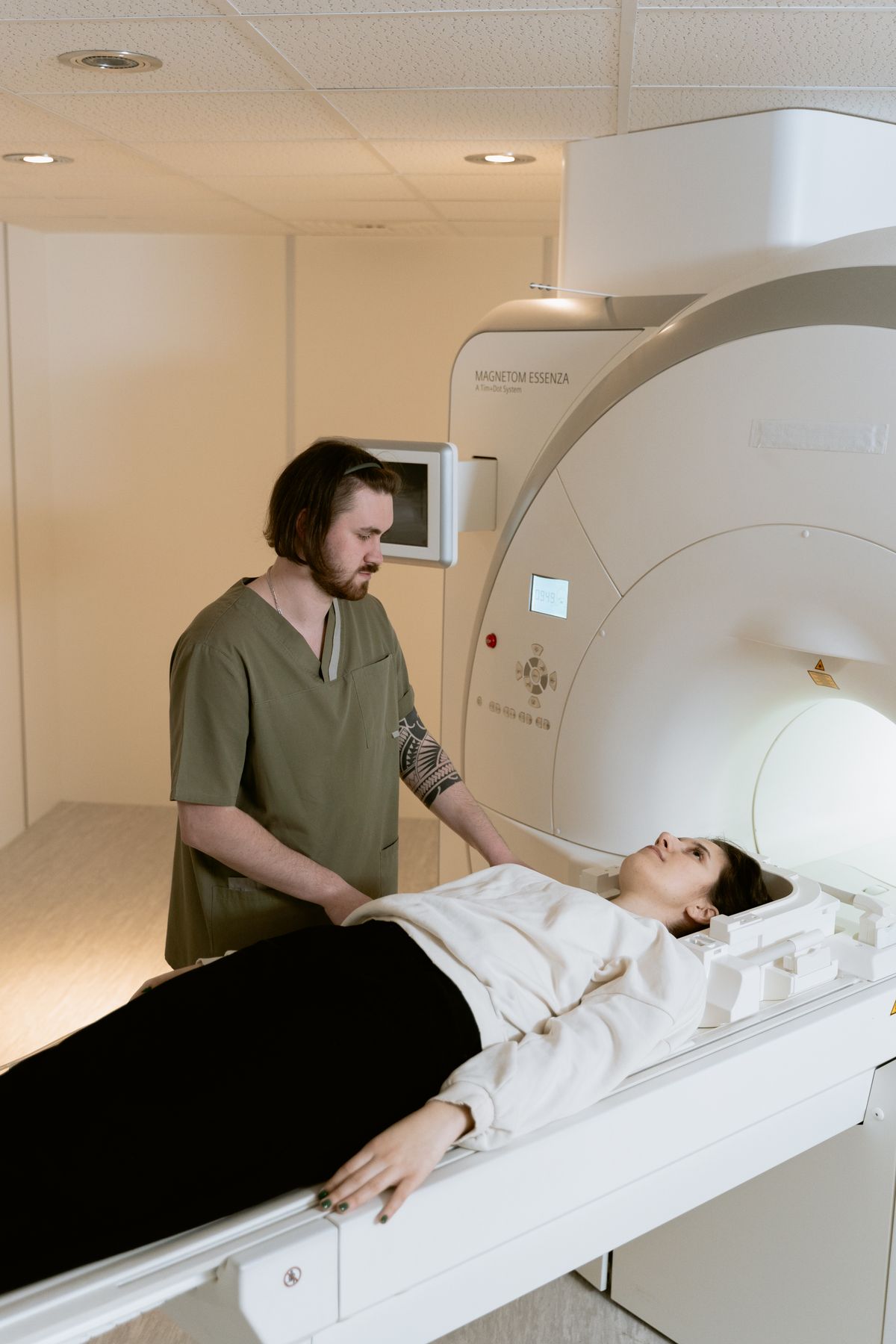 A technologist standing beside a patient lying on an MRI table